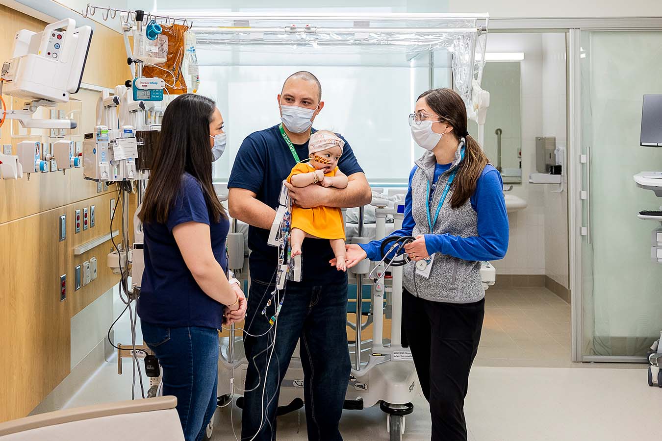 A nurse talks with a family while the dad holds his young daughter in his arms