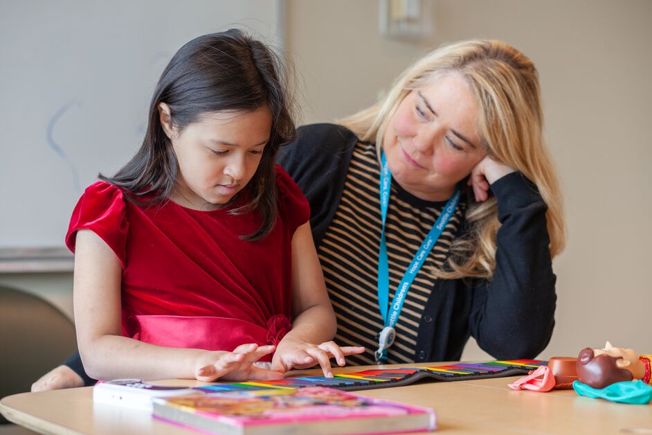 Dr Katrina Davis works with pediatric patient in a red dress.