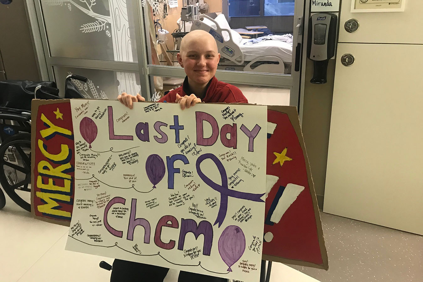 A teenager holds a sign that reads "last day of chemo."