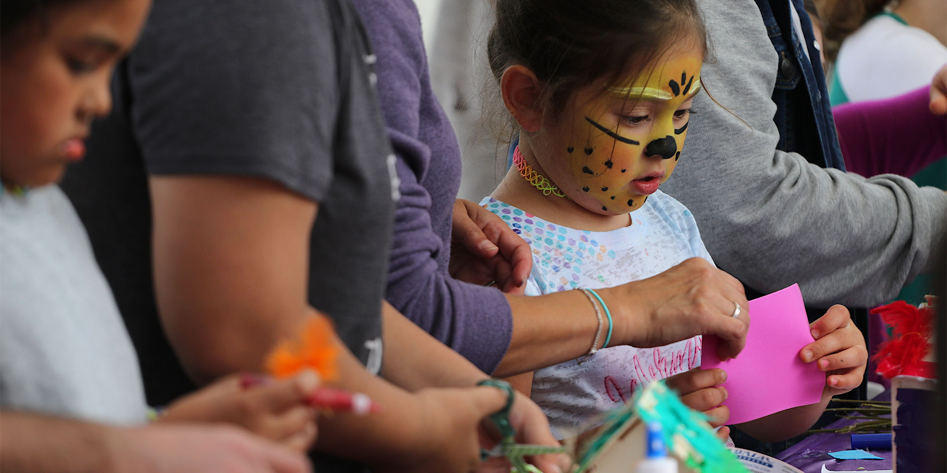 Kids in face paint looking at crafts