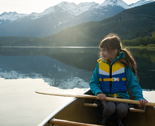 A child wearing a life vest sits in a boat